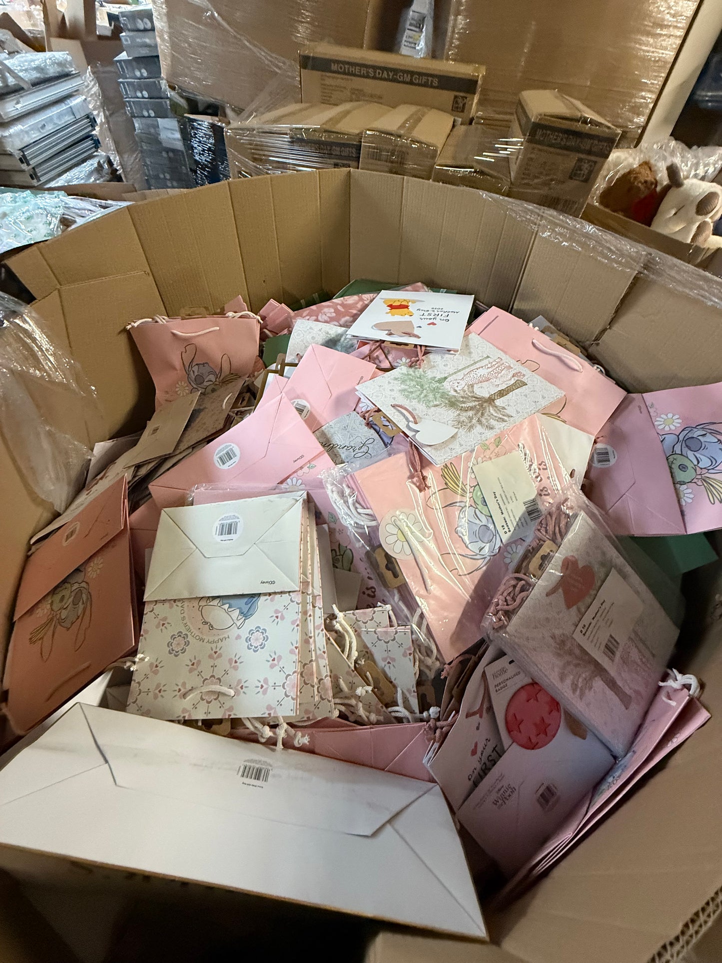 Large box filled with seasonal gift bags overstock, featuring colorful designs and various greeting cards