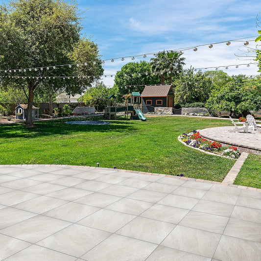Beige outdoor porcelain floor tiles laid in a sunny garden with green grass and playground equipment