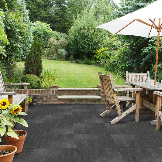 Black outdoor porcelain floor tiles in a spacious garden setting with wooden furniture and plants