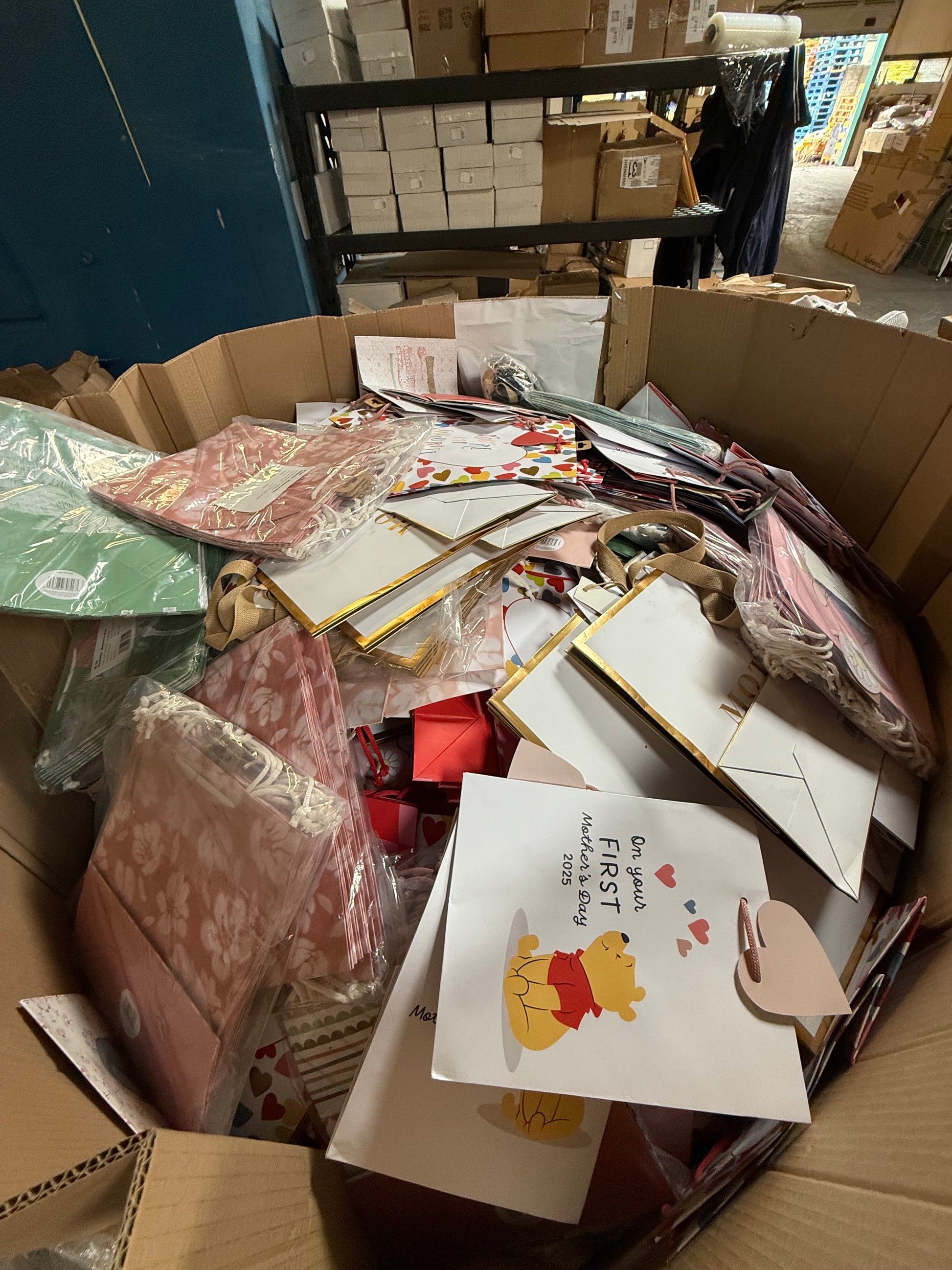 Variety of seasonal gift bags overstock piled in a large cardboard box for sale