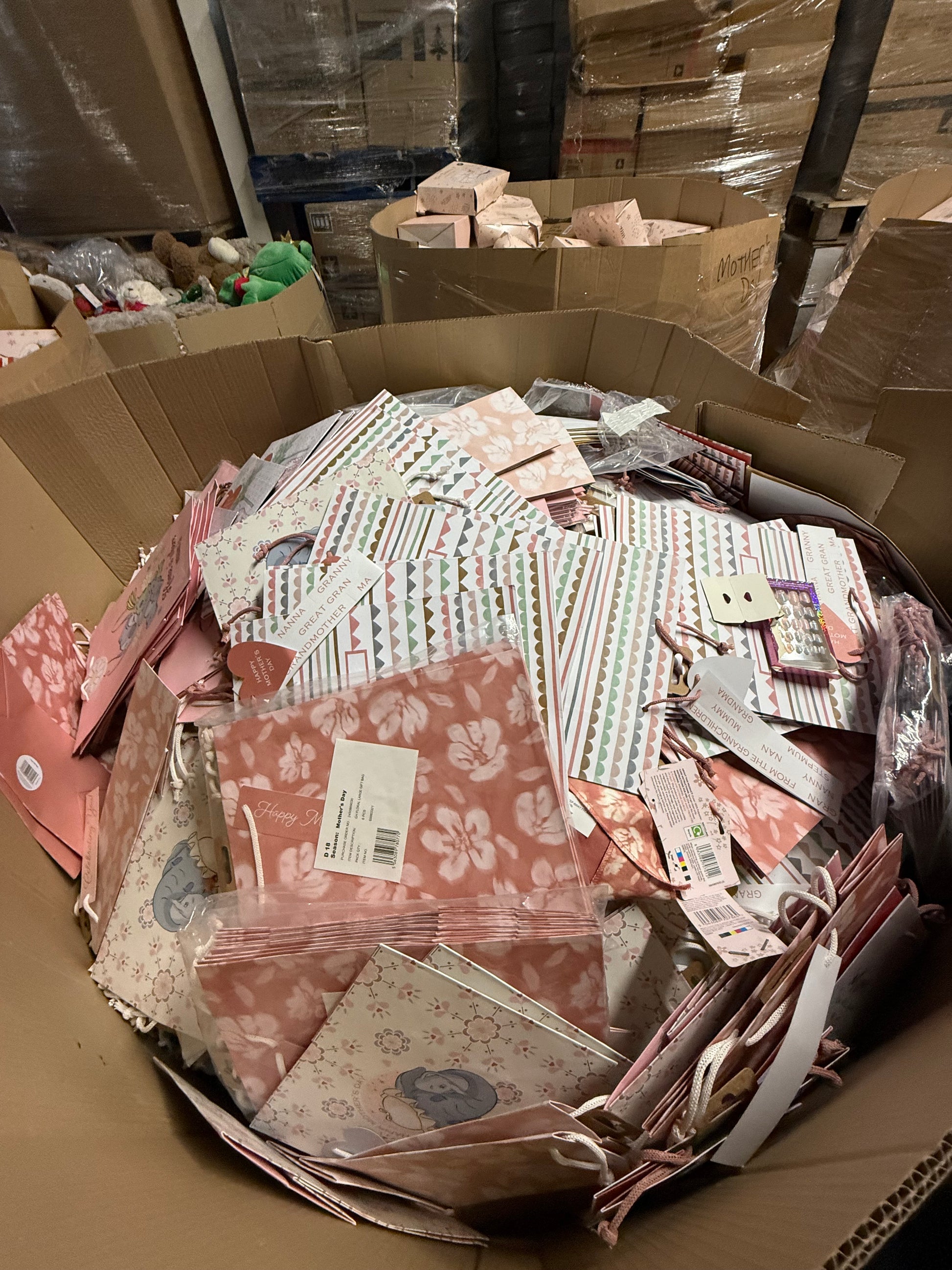 Assorted seasonal gift bags overstock in a large cardboard box for festive gifting needs