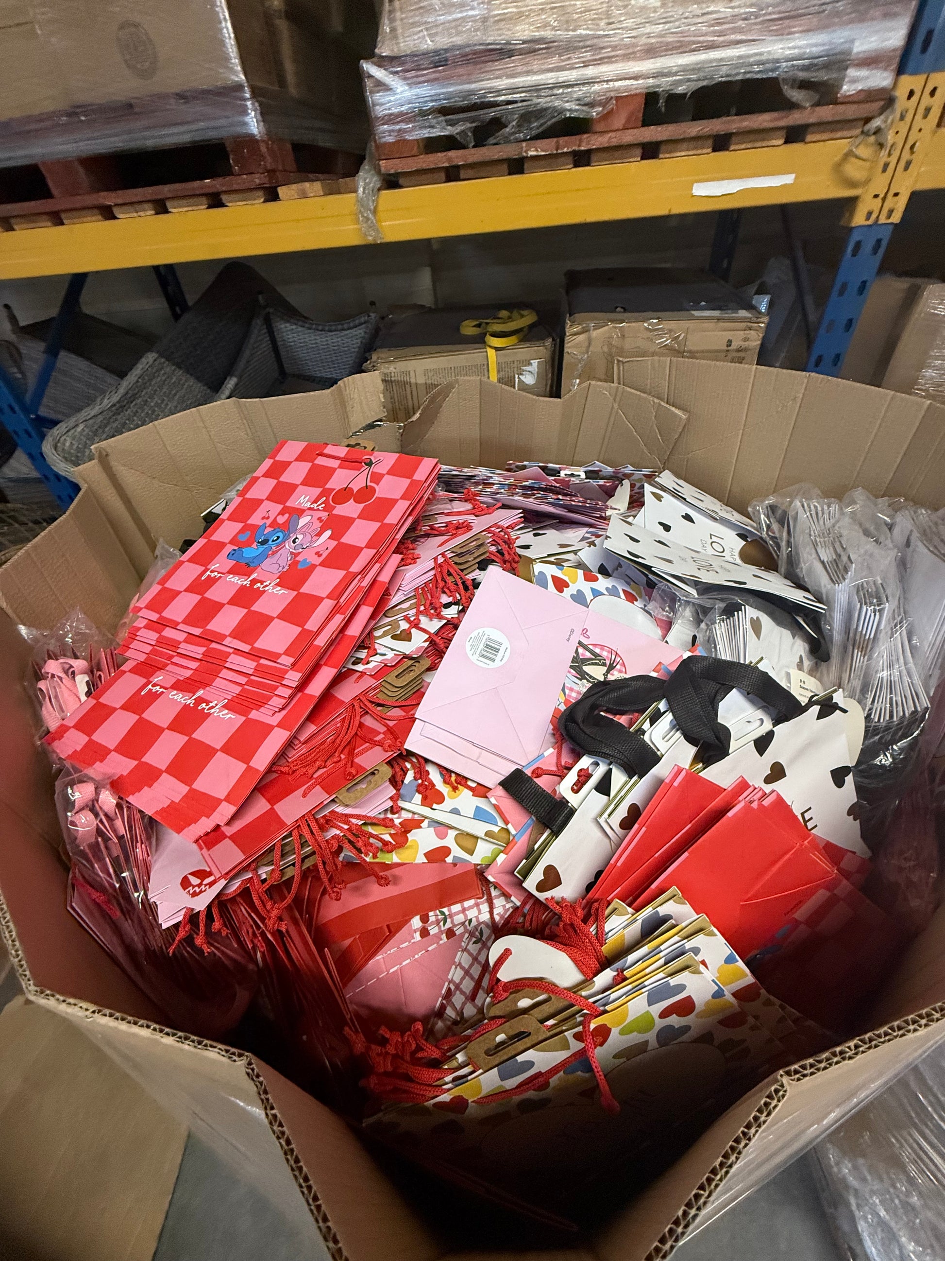 Box filled with seasonal gift bags overstock in various colorful designs and patterns