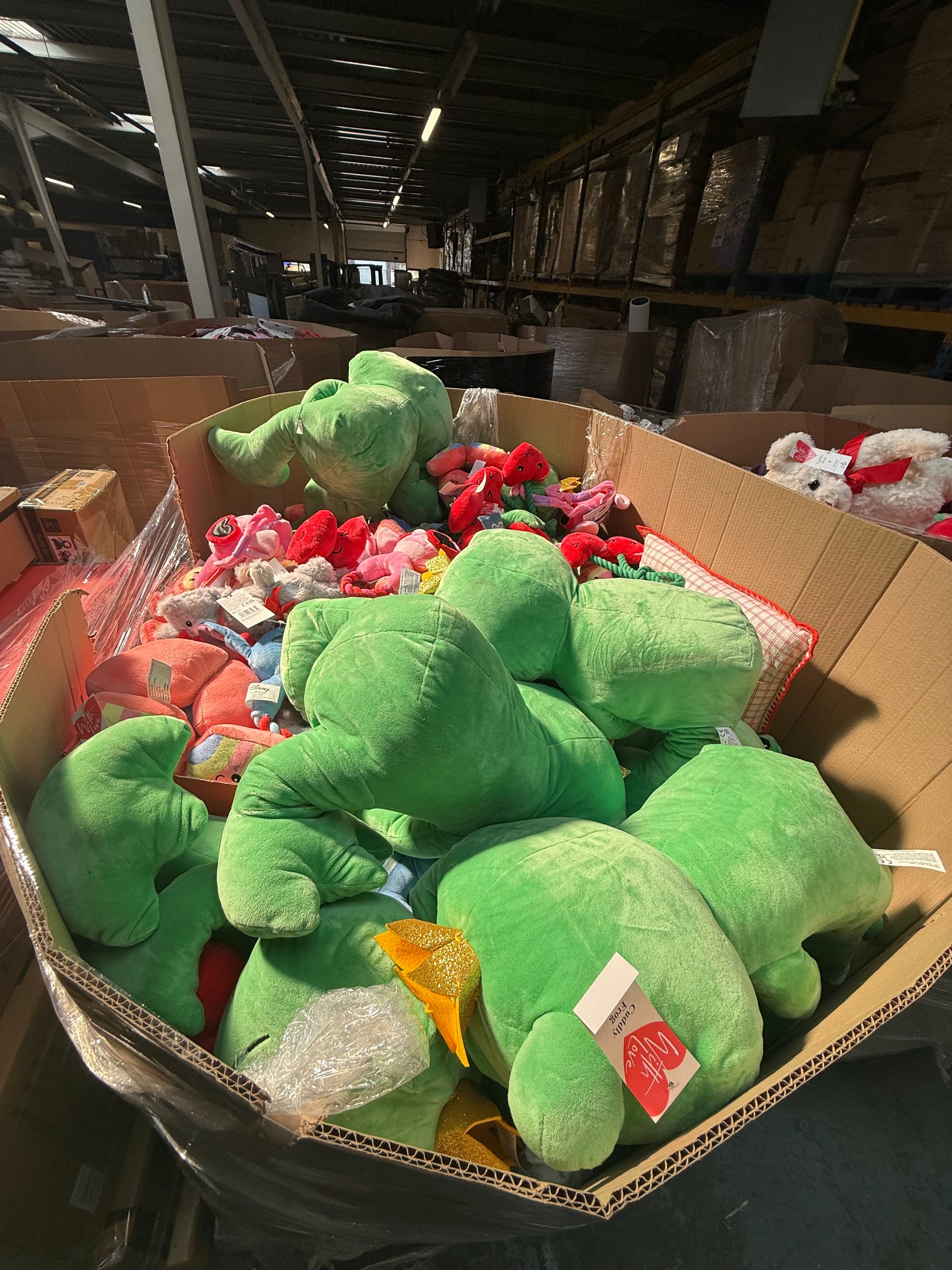 Seasonal soft toys bulk pallet featuring various colorful plush animals in a large storage box