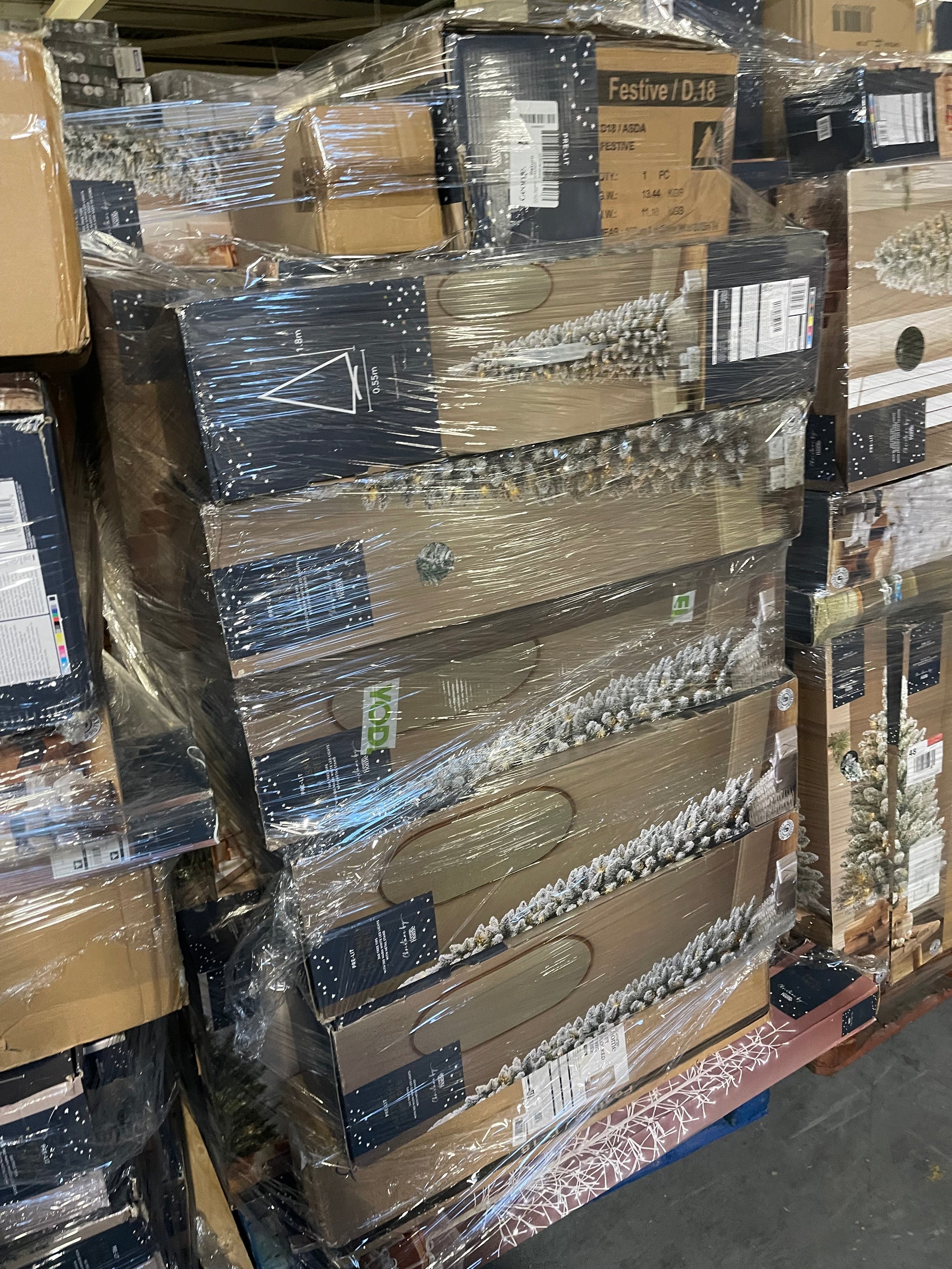 Stacked boxes of wholesale Christmas tree pallets wrapped for delivery and display in a warehouse